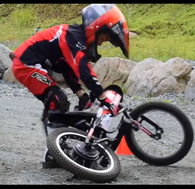 子供が倒れたバイクを持ち上げている様子