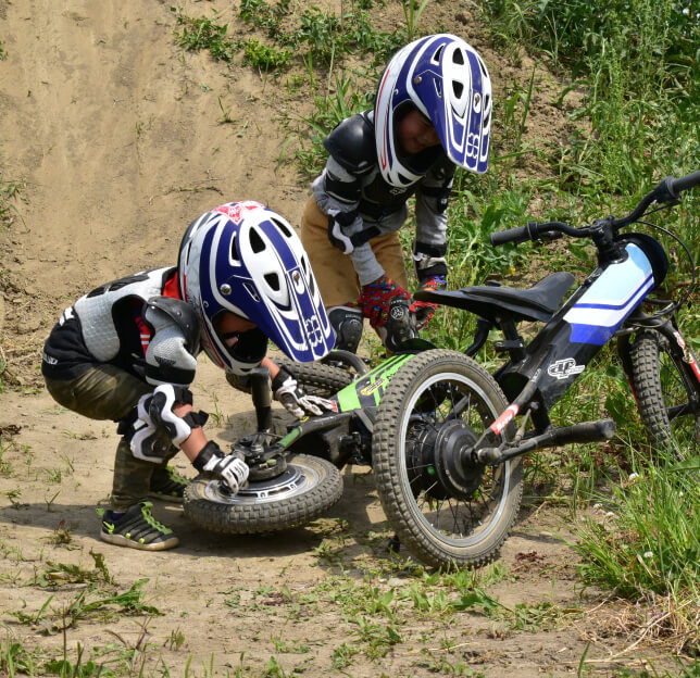 子供が倒れたバイクを持ち上げている様子