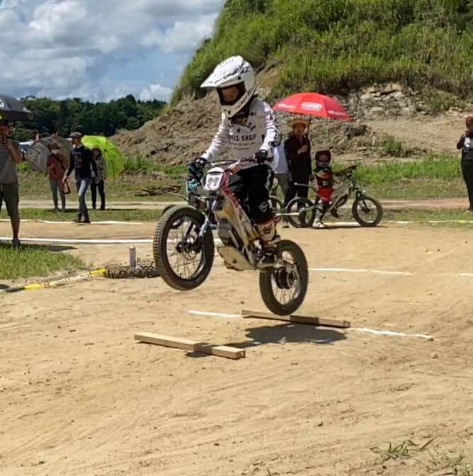 子供がモトバイクで障害物を飛び越えている様子